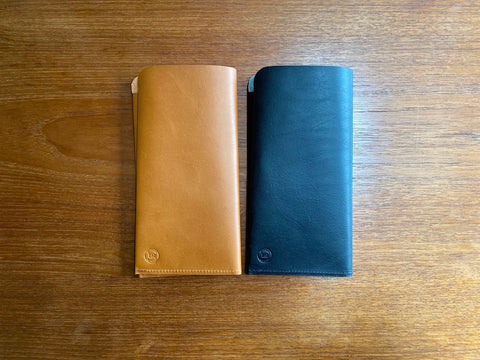 Saddle tan and navy leather Portfolio Inserts on a wooden surface